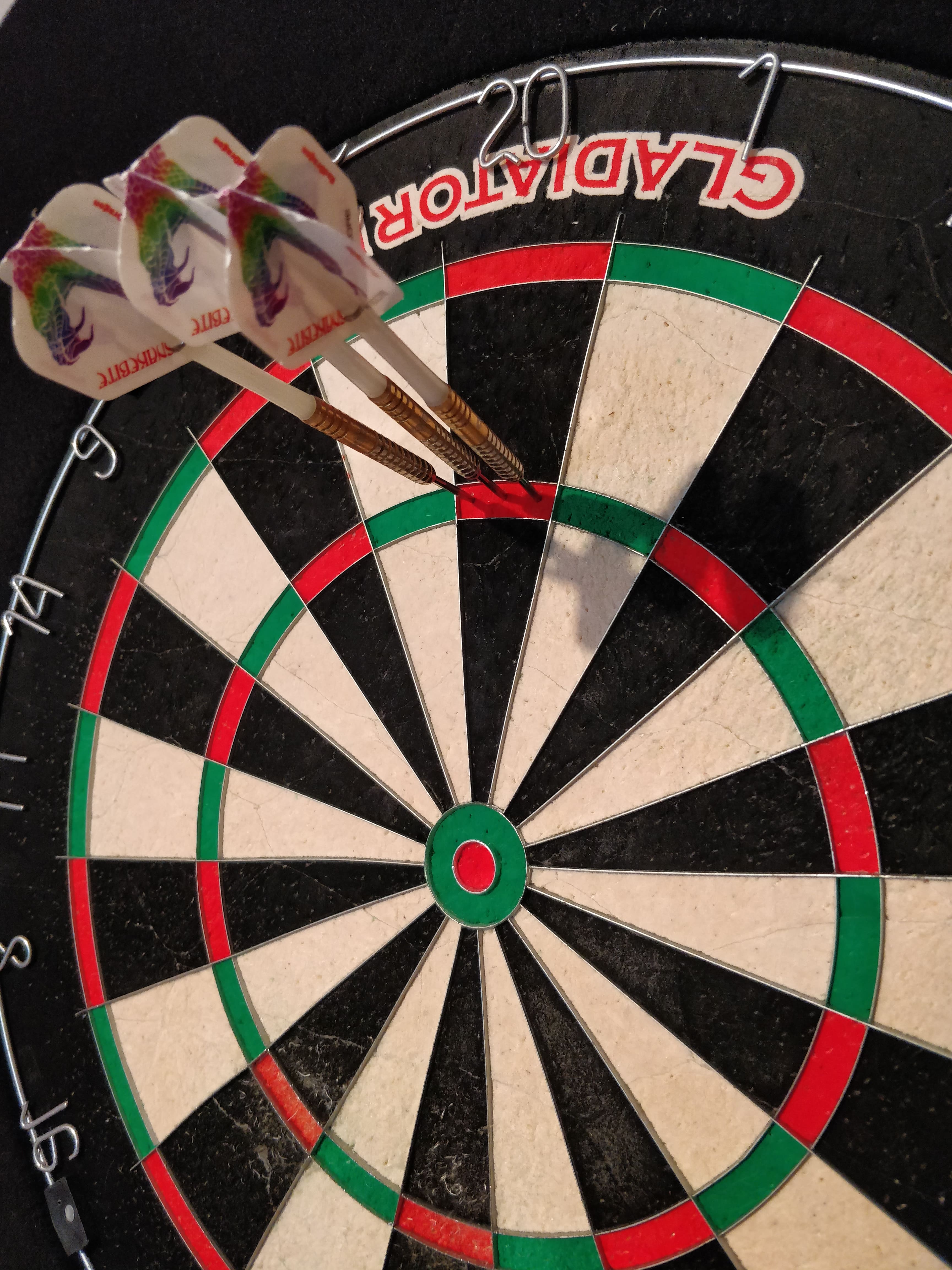 Drei Darts im Triple-20 auf der Dartscheibe beim Training